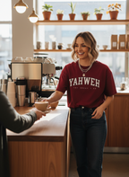 Female barista wearing a red 'YAHWEH' shirt in a coffee shop.