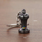 A small black Espresso Tamper keychain with a silver metal chain and key ring, shown on a wooden surface. White measurement lines and text indicate dimensions of 32mm height, 15mm width, and a weight of 22g.