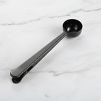 Black measuring spoon on a white marble surface