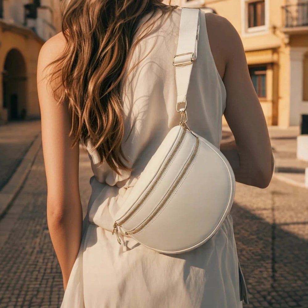 Woman wearing a light-colored dress with a matching Cream Baye Bag on a sunlit street