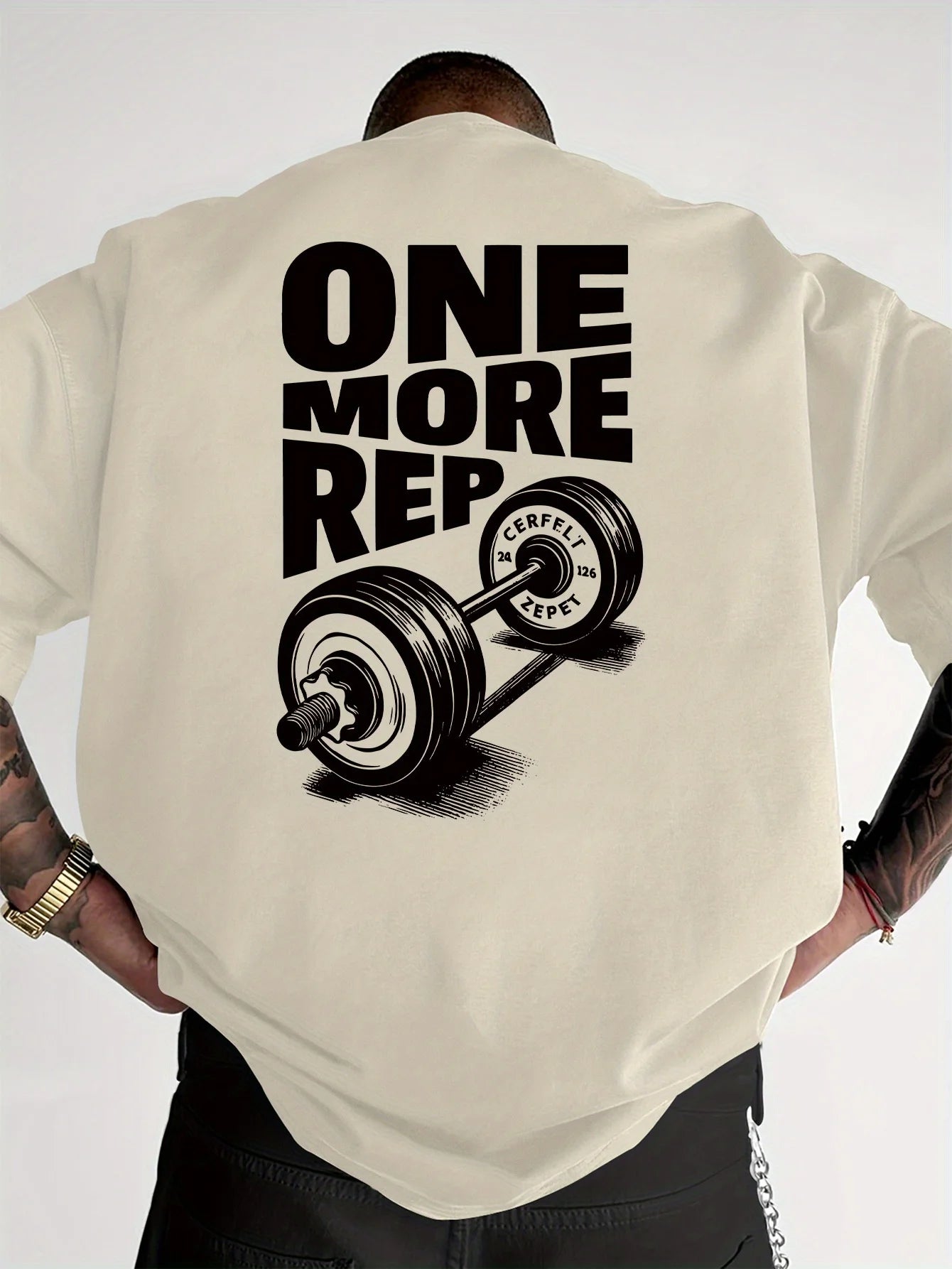 Person wearing a cream t-shirt with 'ONE MORE REP' graphic on the back