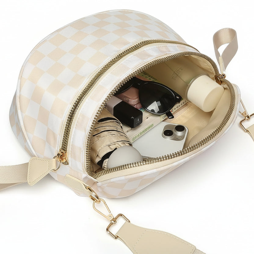 Cream and white checkered Baye Bag with gold zipper and strap, containing various items on a white background