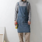 Person wearing a Draper Denim Apron holding a spray bottle against a plain background
