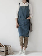 Person wearing a denim apron over a white shirt with a plain background