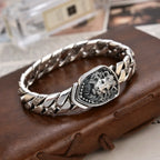 Silver bracelet with lion head design on a brown leather surface