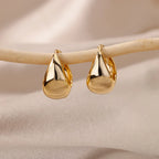 Gold teardrop earrings on a beige background