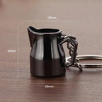 A glossy black miniature pitcher keychain with a silver metal ring and chain, shown on a wooden surface with overlaid dimension lines and text indicating measurements of 28mm, 26mm, and 20mm.