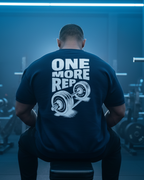 Person wearing a navy blue t-shirt with 'ONE MORE REP' and a barbell graphic on the back.