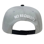 A light gray snapback cap shown from the back, featuring the words 'NO REQUESTS' embroidered in white across the crown and a black adjustable strap.