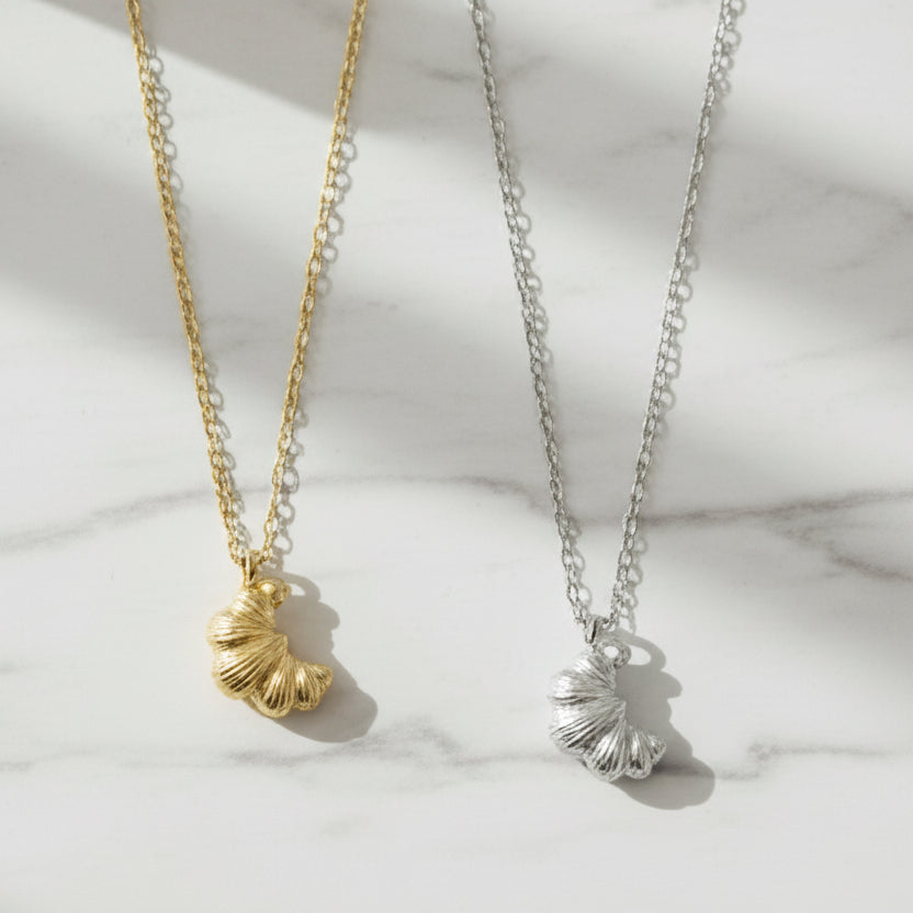 Gold and silver necklaces with Croissant pendants on a marble background