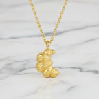 Gold croissant pendant necklace on a marble background