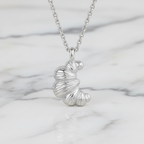 Silver croissant necklace with a unique pendant on a marble surface