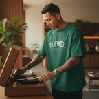Man in green t-shirt with 'YAHWEH' text playing a vinyl record in a cozy room.