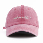 Pink cap with 'overstimulated' text on a white background