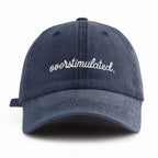 Navy blue cap with 'overstimulated' text on a white background
