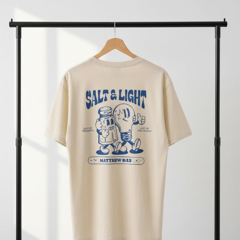 Beige Christian t-shirt with blue "Salt and Light" graphic design and text on a hanger against a white background.