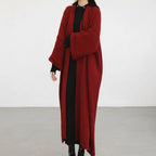 Red knitted cardigan worn by a person on a white background
