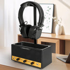 Black and yellow headphone stand with a pair of headphones on a desk.