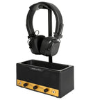 Black headphones on a black and yellow headphone stand with amplifier on a white background
