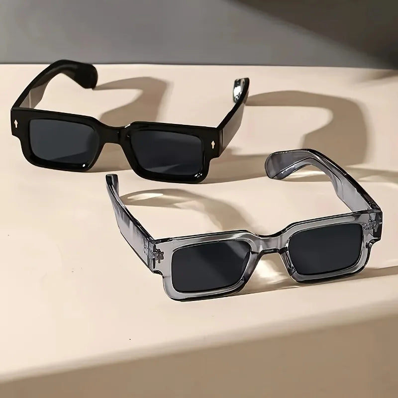 Two pairs of sunglasses on a light surface with a neutral background