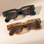 Two pairs of sunglasses, one black and one tortoiseshell, on a beige background.